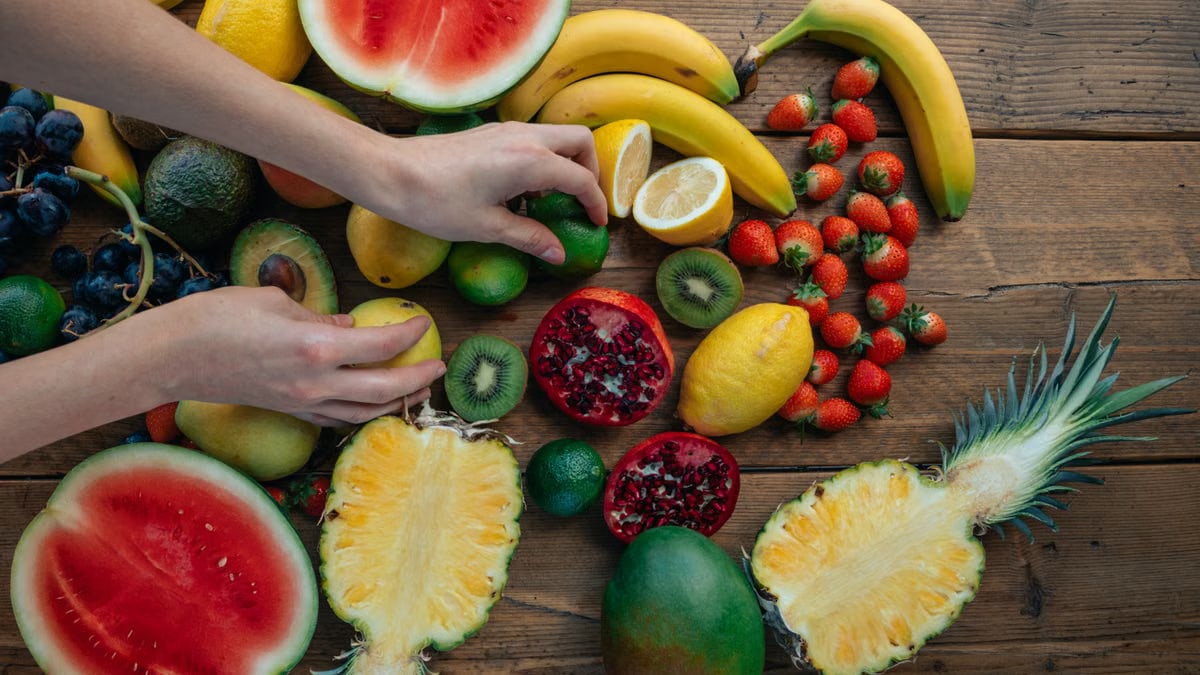A colorful variety of fresh tropical fruits including watermelon, bananas, and more on a wooden surface.